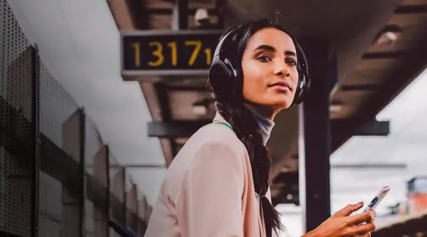 Lady on train platform wearing Audio Technica headphones