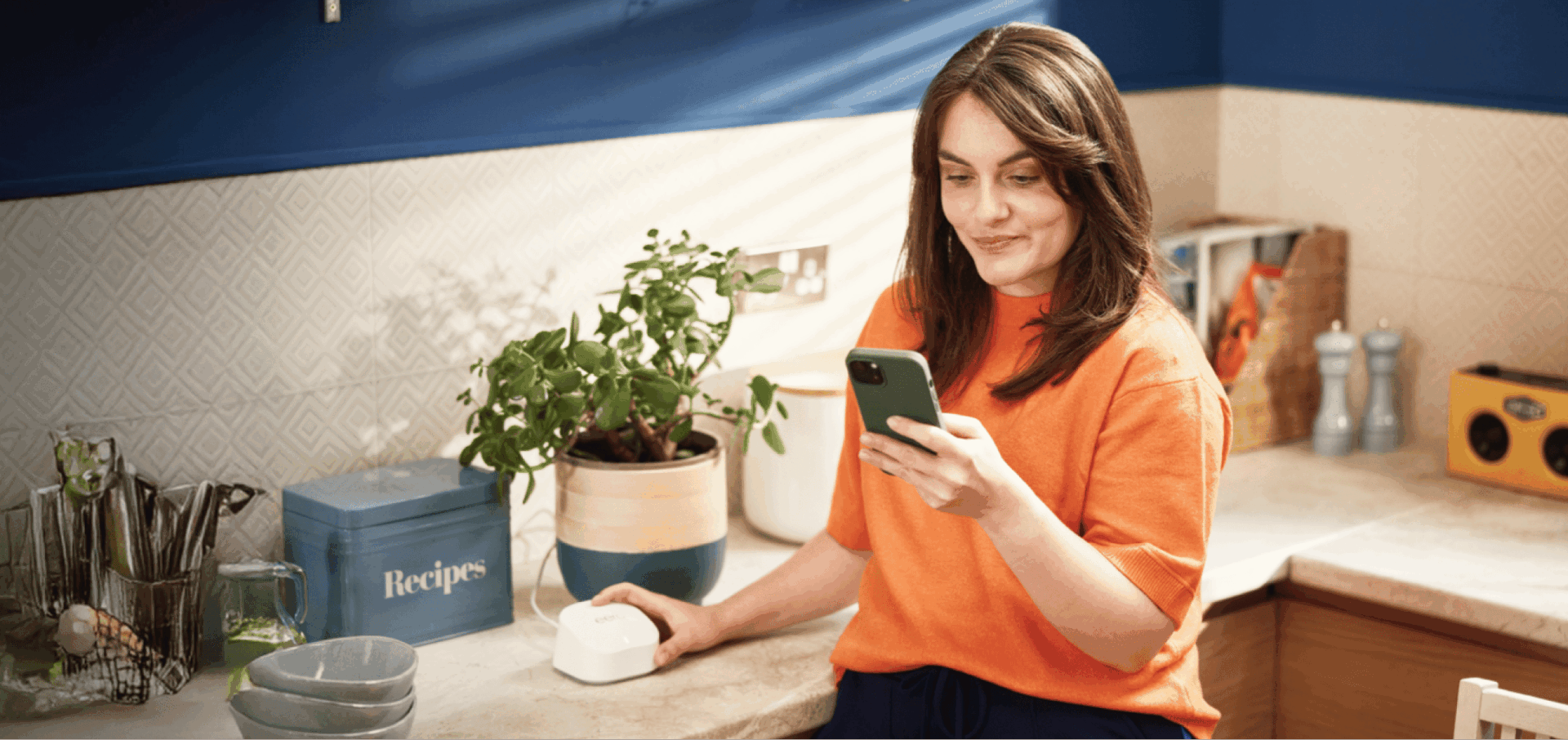 Woman in kitchen using KCOM Eero device